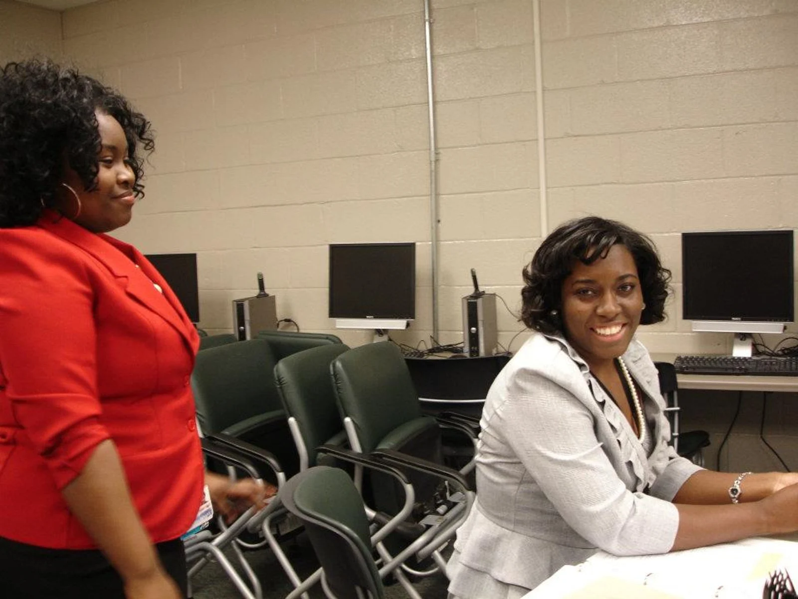 Photo of a woman of colour sat at a desk, smiling and looking a two sheets of paper she's holding with a white version of the MetLife logo superimposed in the middle foreground